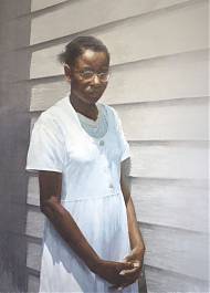Black woman with glasses wearing a white dress in front of a white beach hut.
