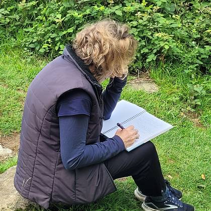 Woman writing outside in garden - writer's retreat.