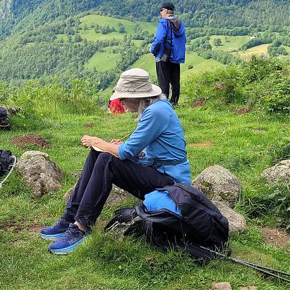 Lady in hat writing in the mountains - creative retreat.