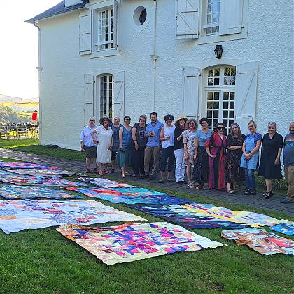 Quilting group outside Clos Mirabel with quilts on grass.