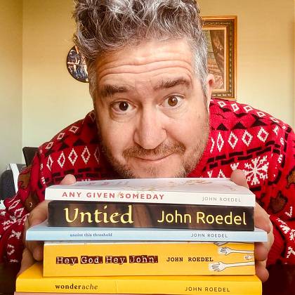 John Roedel pictured in front of his published books.