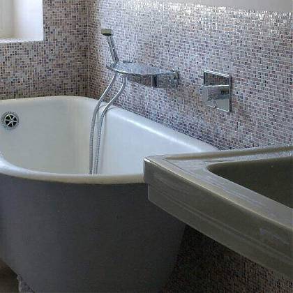 Roll top bath, small mosaic wall tiles in pink tones.