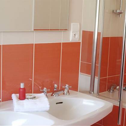 Bathroom with double sink, mirror, peach colour tiles, bath with shower.