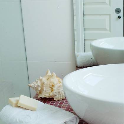 White wash basin, with silver tap, towel with soap and shell to the left.