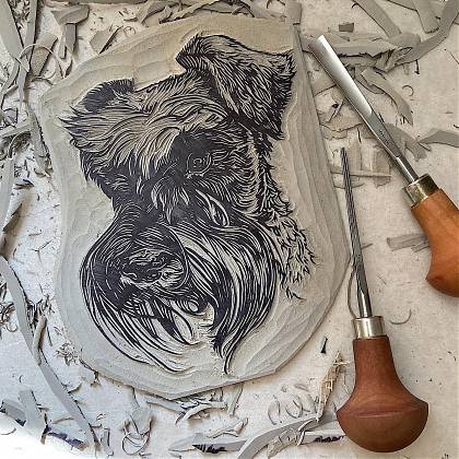 Lino cut of a dog with cutting tools to the right.