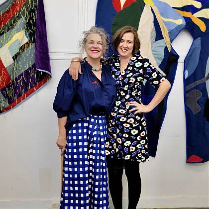 Chloe Briggs and Angela Maddock in front of quilting artwork.