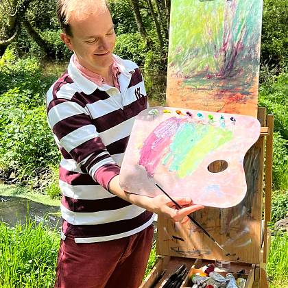 Peter Keegan wearing striped top in front of easel doing a demo for painting holidays.